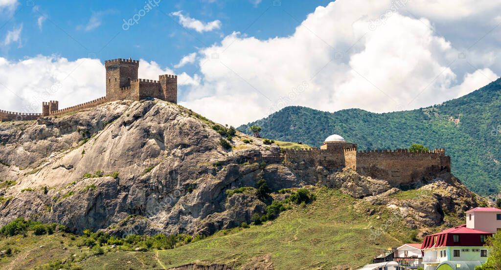 Landscape of Crimea, scenic view of old Genoese fortress in Sudak. It is landmark of Crimea. Panorama of medieval ruins at mountain top over Black Sea. Concept of summer travel in Crimea.