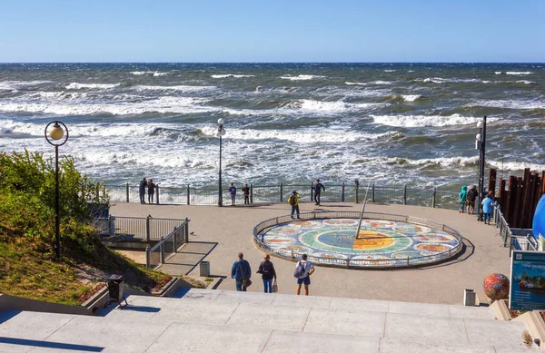 Svetlogorsk, Rusya - 30 Haziran 2018: Fırtınalı bir günde gezinti güvertesinde güneş saati, Svetlogorsk, Kaliningrad bölgesi. Svetlogorsk 'un simgesidir. İnsanlar yaz aylarında Baltık Denizi 'nin setinde yürür..