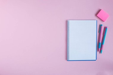 Pembe arka planda okul defteri ve kırtasiye malzemesi..