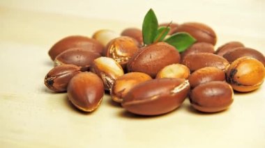 Ahşap arka planda yeşil yapraklı Argan fındıkları.