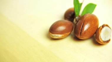 Ahşap arka planda yeşil yapraklı Argan fındıkları. 