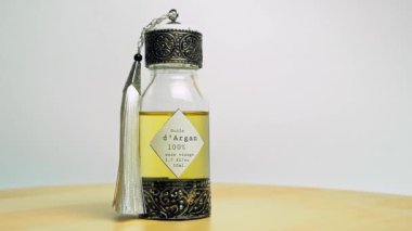 Oryantal cam ve metal bir şişedeki Argan yağı ahşap masa ve beyaz arka planda.