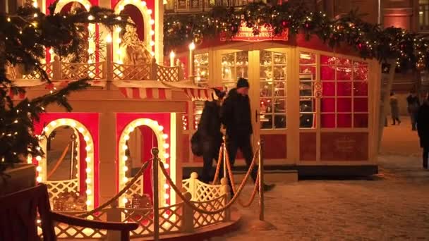 MOSCOW - DEC 17, 2020: Feestelijke nieuwjaars- en kerstvakantie in Snowy Moskou. Een menigte mensen loopt tussen kerstbomen op Manezjnaja plein in de buurt van het Rode Plein en het Kremlin. Heldere lichten schijnen op de — Stockvideo