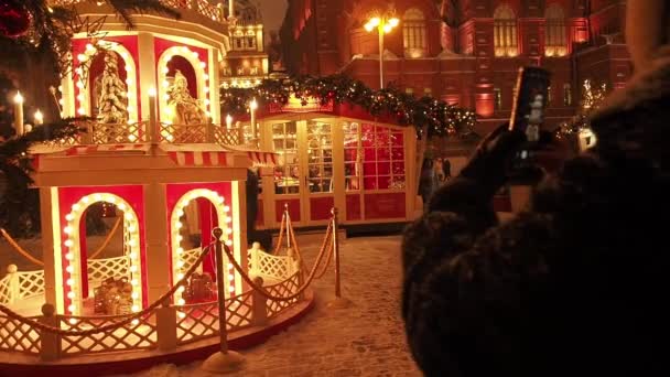 MOSKW - GRUDZIEŃ 17, 2020: Uroczysty Nowy Rok i Święta Bożego Narodzenia w Snowy Moskwa. Tłum ludzi robi zdjęcia i spacery wśród choinek na placu Manezhnaya w pobliżu Placu Czerwonego i Kremla. Bystry — Wideo stockowe