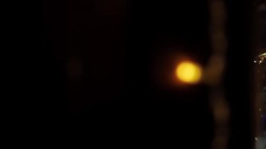 Genç kız bir Noel ağacının camından bakar ve gülümser. Genç bir kız süslü bir Noel ağacıyla eve bakıyor ve hayranlık dolu ve büyüleyici bir bakışla duruyor. Sihirli an ve