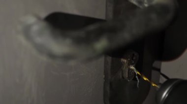 Matkapla kapı kilidini kırmak. Bir adam kapıyı açmak için bir anahtar deliği açar. Hırsız karanlıkta kapıyı kırmaya çalışıyor.