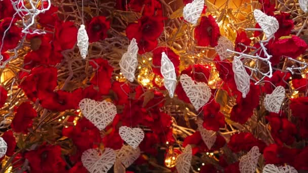 Saint-Valentin économiseur d'écran. Décorations blanches en forme de coeur suspendues à une balançoire d'arbre et de spin soufflé par le vent sur le fond de lumières éclairantes et de branches sèches avec des fleurs — Video