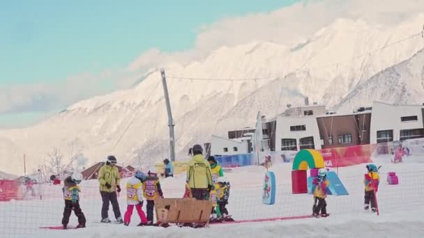 Rosa Khutor, Polana Krasnaya, Soczi. Region Krasnodarski, Rosja - 11 lutego 2020 r.: Szkolenie młodej drużyny narciarskiej. Trener z zespołem małych dzieci na lekcji przygotowania do jazdy na nartach. — Wideo stockowe