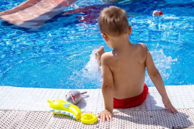 Havuzda su tabancasıyla oynayan mutlu bir çocuk. Rekreasyon