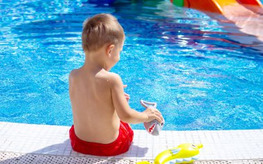 Havuzda su tabancasıyla oynayan mutlu bir çocuk. Rekreasyon