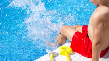 Havuzda su tabancasıyla oynayan mutlu bir çocuk. Rekreasyon