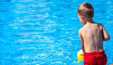 Havuzda su tabancasıyla oynayan mutlu bir çocuk. Rekreasyon