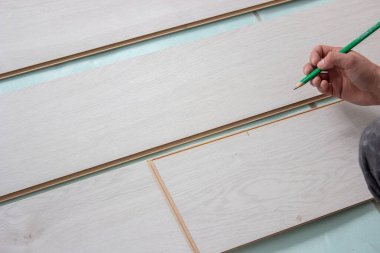 İşçilerin elleri ahşap kaplama döşeme döşemesi kuruyor. Ahşap zeminli ve ölçülü ev tadilatı. seçici odak