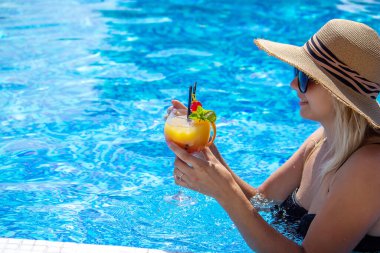 Kız havuzda kokteyl içiyor. seçici odak