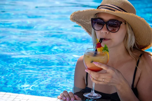 Kız havuzda kokteyl içiyor. seçici odak