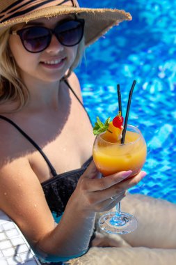 Kız havuzda kokteyl içiyor. Doğa. seçici odak