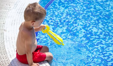 Mutlu çocuk havuzda su tabancasıyla oynuyor. seçici odak