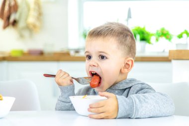 Çocuklar mutfaktaki masada makarna çeviriyor. seçici odak