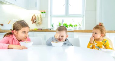 Çocuklar mutfaktaki masada makarna çeviriyor. seçici odak