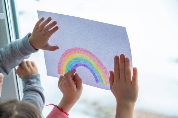 drawn rainbow on a sheet. Children hold a leaf with a rainbow near the window. selective focus