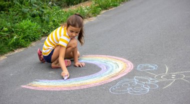 Bir çocuk asfalta bir gökkuşağı çizer. Seçici odaklanma. çocuk.