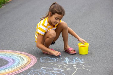 Bir çocuk asfalta bir gökkuşağı çizer. Seçici odaklanma. çocuk.