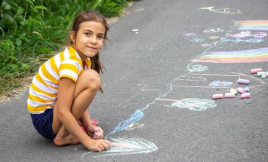Bir çocuk asfalta bir gökkuşağı çizer. Seçici odaklanma. çocuk.