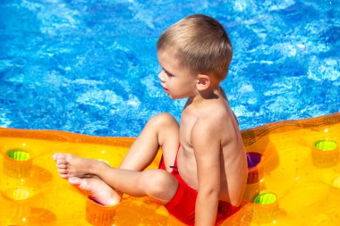 Dinlen. Çocuk havuzda şişme bir yatakta yüzüyor. seçici odak