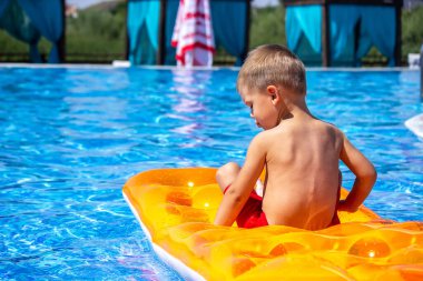 Dinlen. Çocuk havuzda şişme bir yatakta yüzüyor. seçici odak
