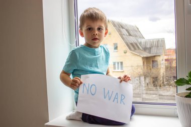 Küçük bir çocuk elinde savaşa hayır yazılı bir kağıt parçası tutuyor. seçici odak