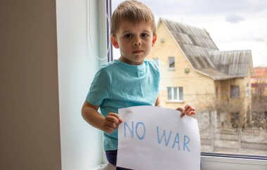 Küçük bir çocuk elinde savaşa hayır yazılı bir kağıt parçası tutuyor. seçici odak