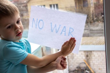 Küçük bir çocuk elinde savaşa hayır yazılı bir kağıt parçası tutuyor. seçici odak