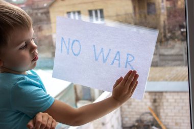 Küçük bir çocuk elinde savaşa hayır yazılı bir kağıt parçası tutuyor. seçici odak