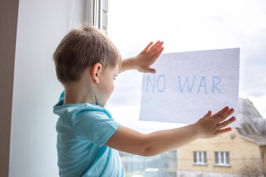 Küçük bir çocuk elinde savaşa hayır yazılı bir kağıt parçası tutuyor. seçici odak