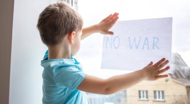 Küçük bir çocuk elinde savaşa hayır yazılı bir kağıt parçası tutuyor. seçici odak