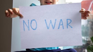 Küçük bir çocuk elinde savaşa hayır yazılı bir kağıt parçası tutuyor. seçici odak