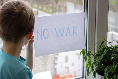 Küçük bir çocuk elinde savaşa hayır yazılı bir kağıt parçası tutuyor. seçici odak