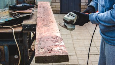 Bir adam tahtayı öğütüyor. Tahtalardan eski boyaları çıkarıyorum. Marangozluk işi. seçici odak