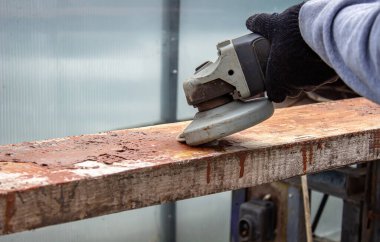 Bir adam tahtayı öğütüyor. Tahtalardan eski boyaları çıkarıyorum. Marangozluk işi. seçici odak