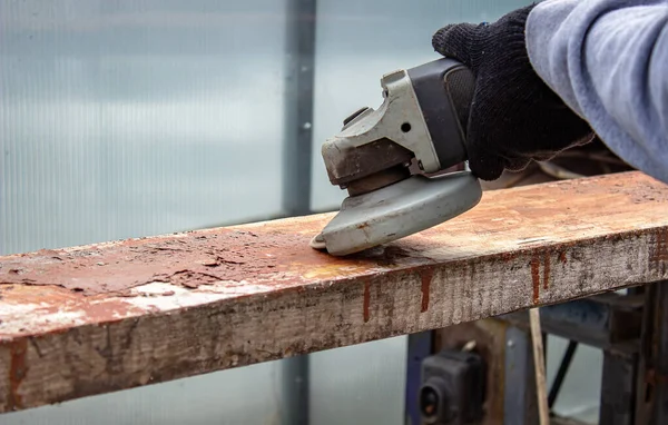 Bir adam tahtayı öğütüyor. Tahtalardan eski boyaları çıkarıyorum. Marangozluk işi. seçici odak