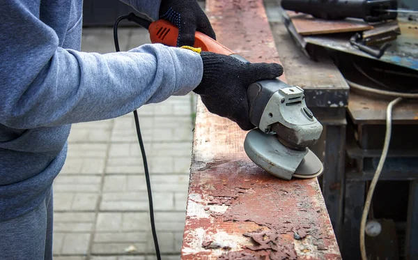 Bir adam tahtayı öğütüyor. Tahtalardan eski boyaları çıkarıyorum. Marangozluk işi. seçici odak