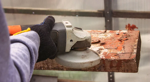 Bir adam tahtayı öğütüyor. Tahtalardan eski boyaları çıkarıyorum. Marangozluk işi. seçici odak