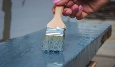 Kız fırçayla tahta boyuyor. Gri boyalı boya. seçici odak