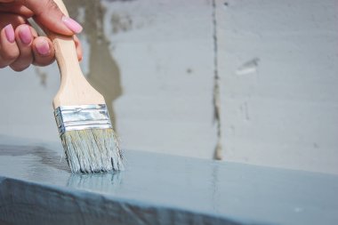 Kız fırçayla tahta boyuyor. Gri boyalı boya. seçici odak