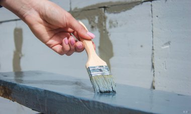 Kız fırçayla tahta boyuyor. Gri boyalı boya. seçici odak