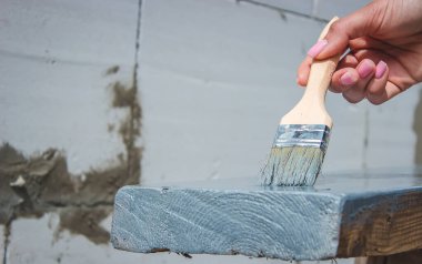 Kız fırçayla tahta boyuyor. Gri boyalı boya. seçici odak