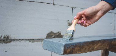 Kız fırçayla tahta boyuyor. Gri boyalı boya. seçici odak