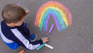 Bir çocuk asfalta bir gökkuşağı çizer. Seçici odaklanma. çocuk.