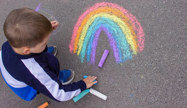 Bir çocuk asfalta bir gökkuşağı çizer. Seçici odaklanma. çocuk.