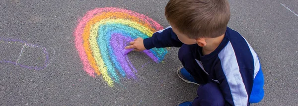 A child draws a rainbow on the asphalt. Selective focus. kid.